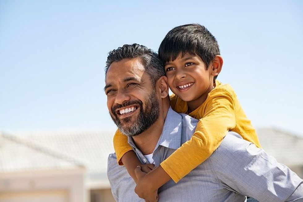 Happy child enjoying ride on father back outdoor 