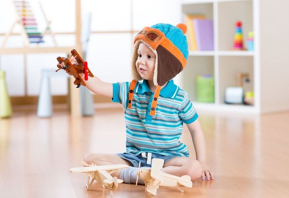 Happy child toddler playing with toy airplane and dreaming of becoming a pilot