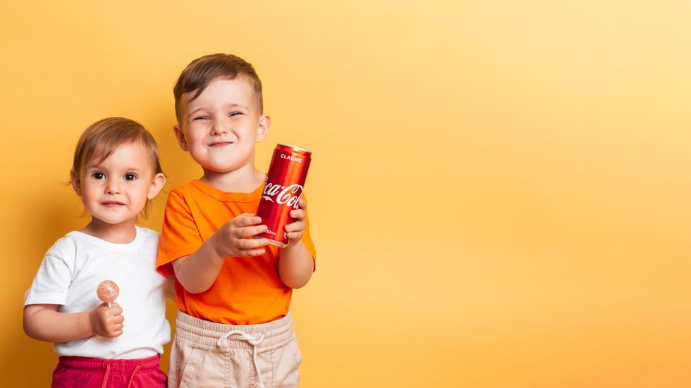 Happy children brother and sister with a can of Coca-Cola and a lollipop in hands