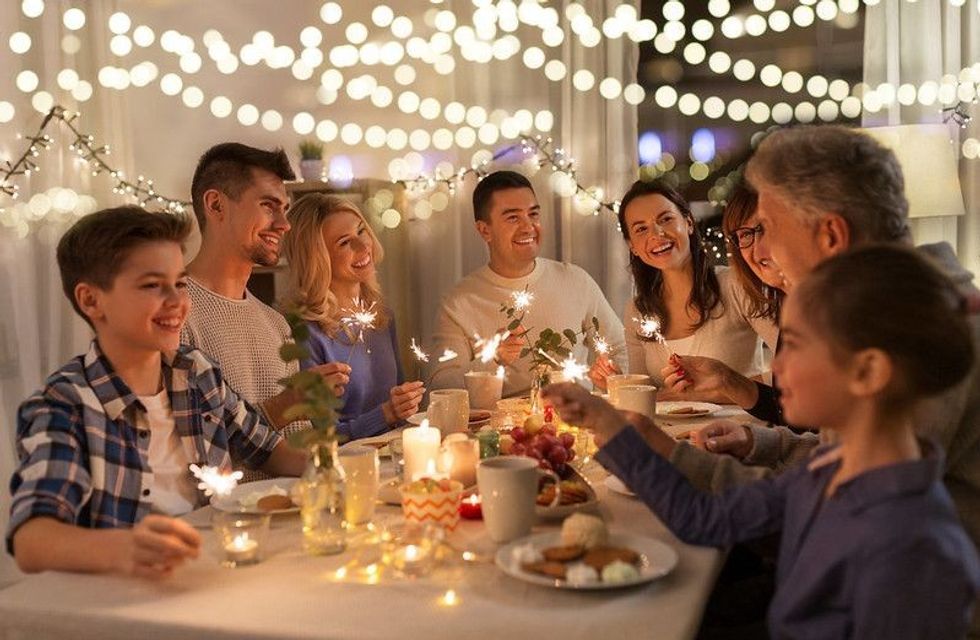 Happy family with sparklers having fun at dinner party at home.