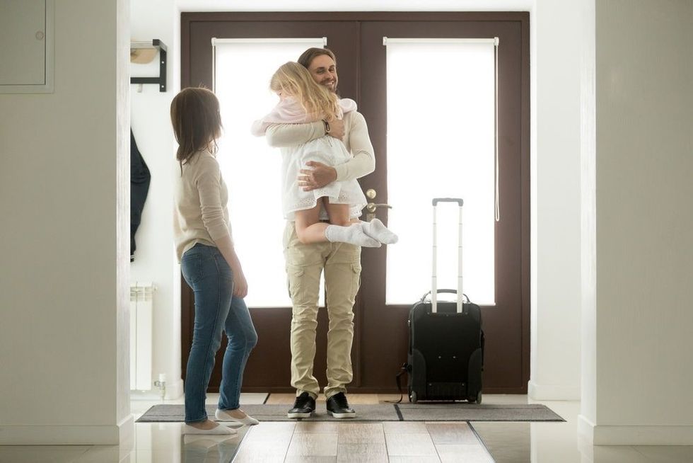 Happy father arrived home returning after business trip with baggage.