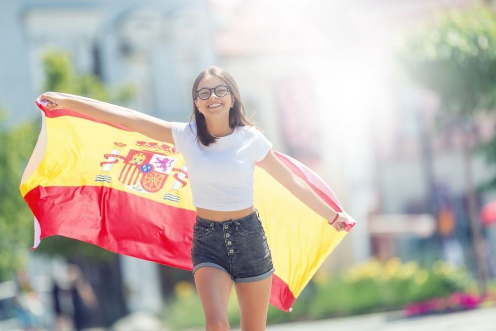 Happy girl tourist walking in the street with spanish flag.