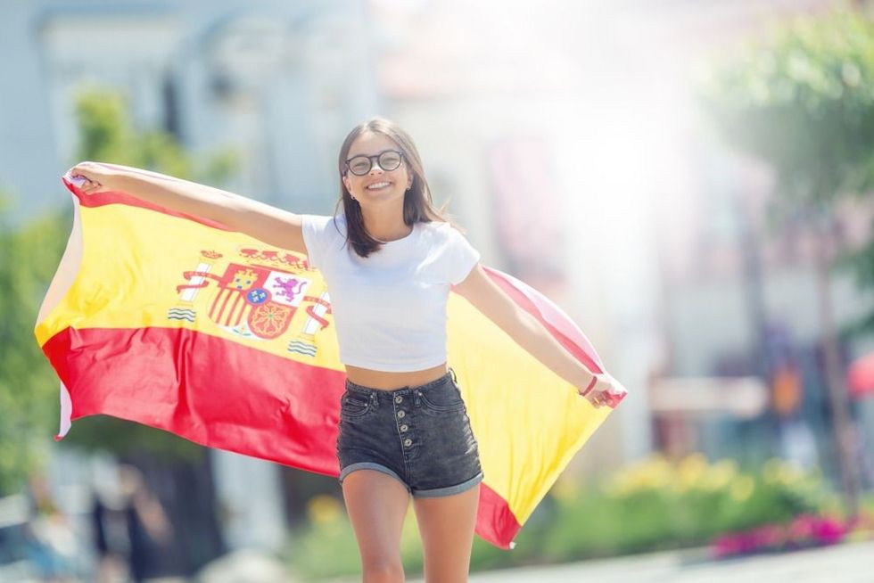 Happy girl tourist walking in the street with spanish flag.