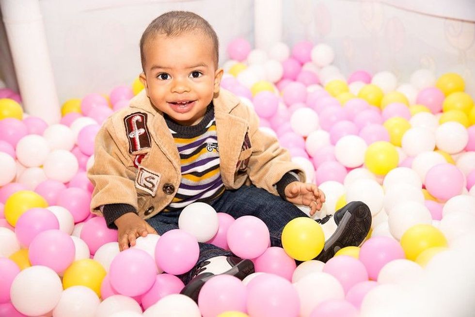 Happy kid sitting in colorful balls.