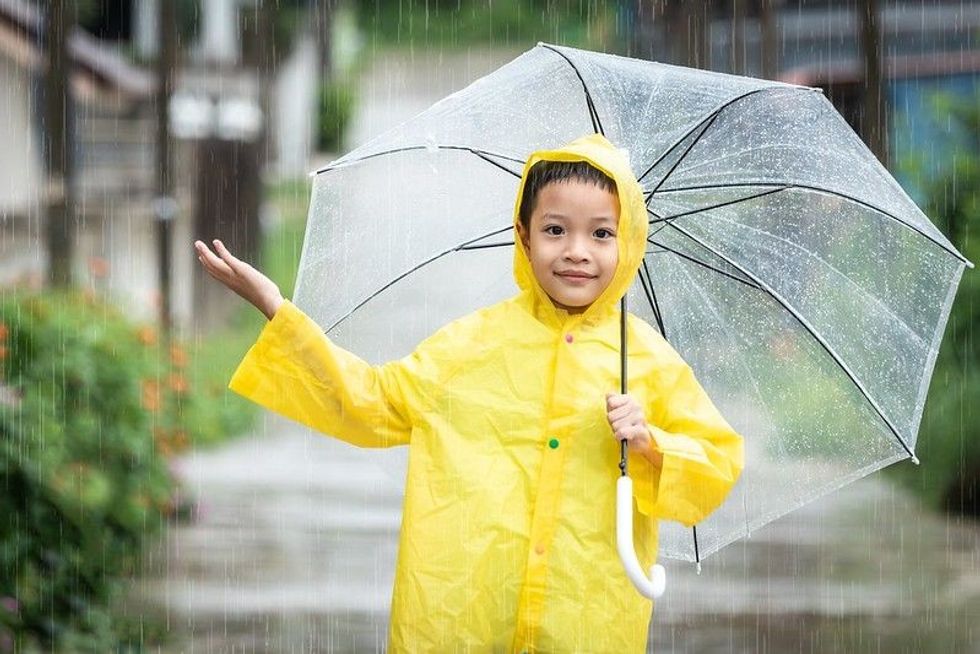 Happy little boy having fun playing in the April rain
