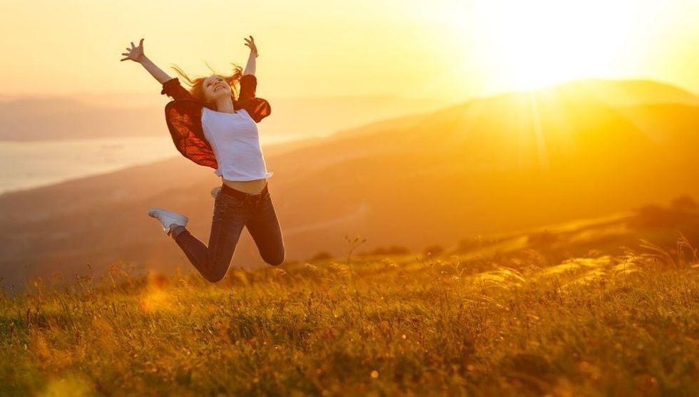 Happy woman jumping at sunset