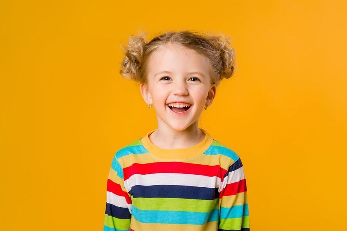 Happy young girl smiling against yellow background