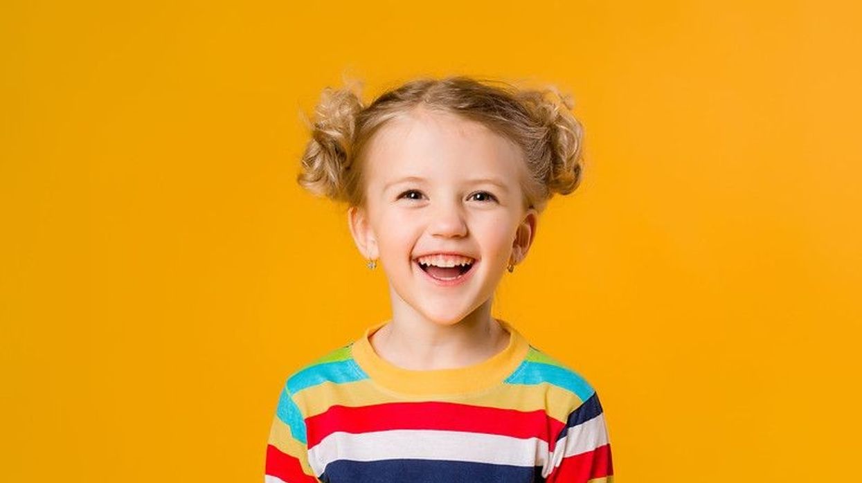 Happy young girl smiling against yellow background
