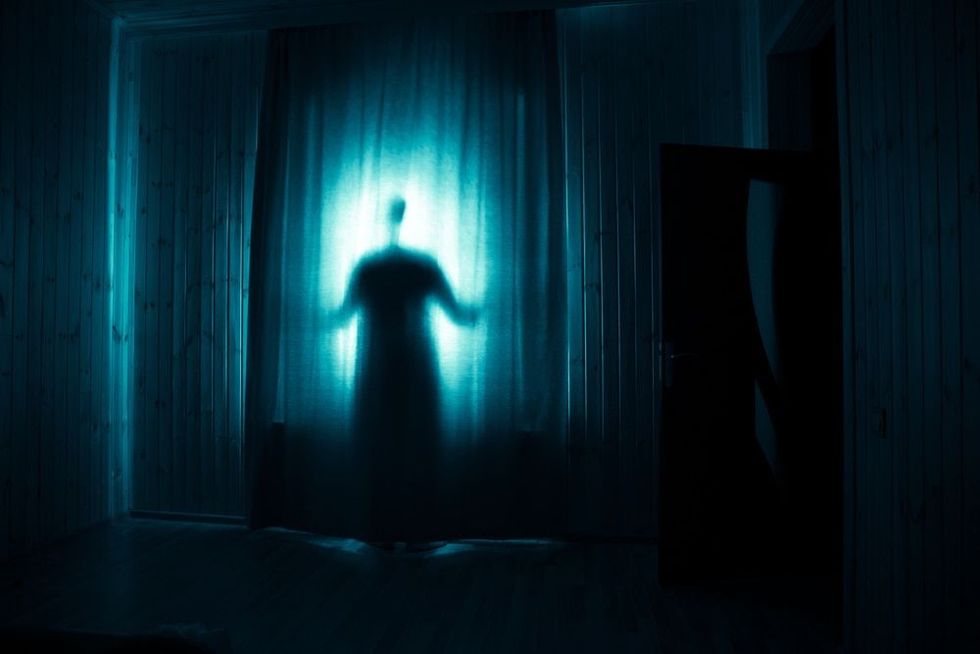 Horror silhouette in window with curtain inside bedroom at night