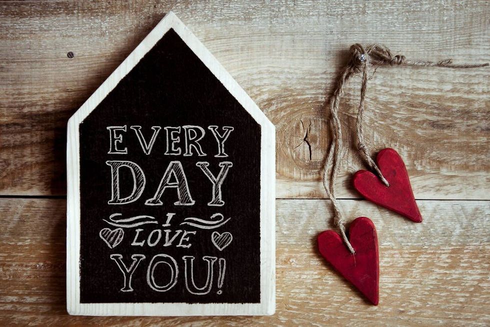 house shaped chalk board "Every day I love you" with two red vintage hearts and rustic old wooden background