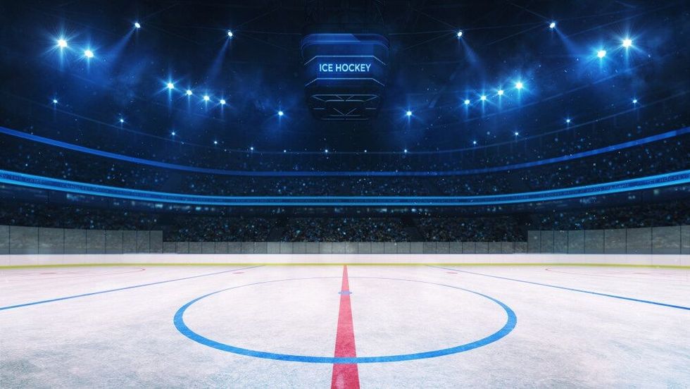 Ice hockey rink and illuminated indoor arena with fans.