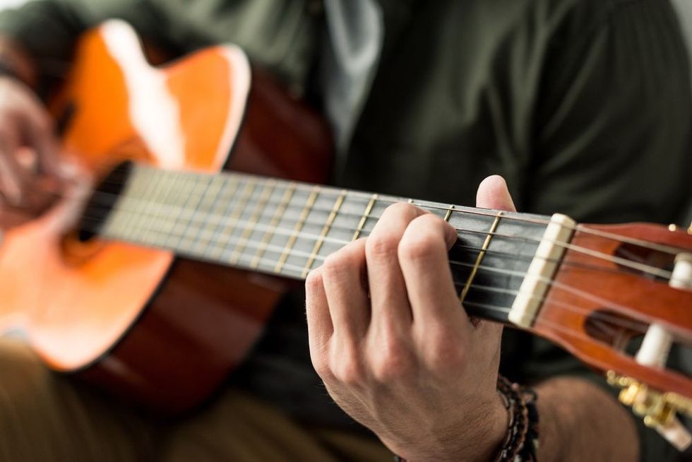 Image of a man playing chord on acoustic guitar