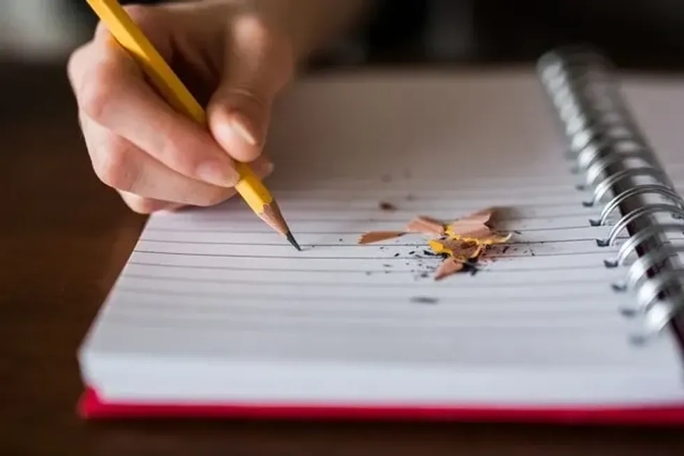 Image showing a kid's hand writing with a pencil on  book