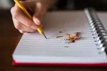 Image showing a kid's hand writing with a pencil on book
