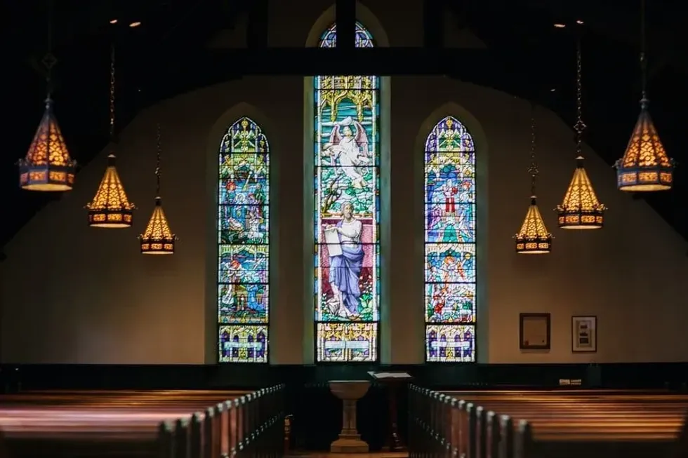 Interior of a church with beautifully detailed stained glass windows depicting religious scenes.