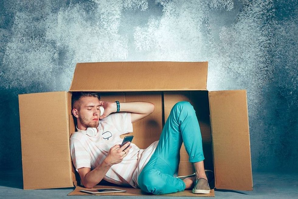 Introvert Man sitting inside box and working with phone