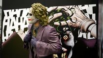 Joker statue in front of a print from the graphic novel by Alan Moore