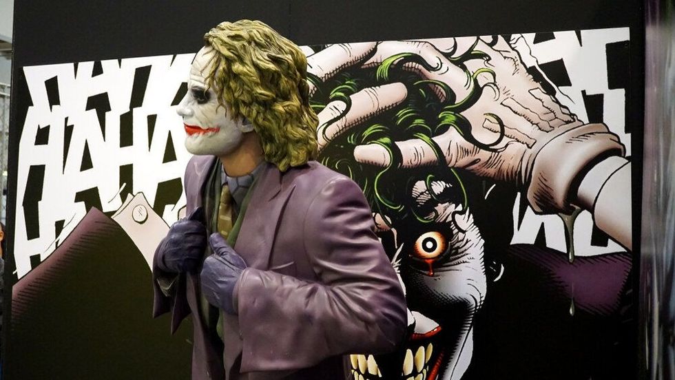 Joker statue in front of a print from the graphic novel by Alan Moore