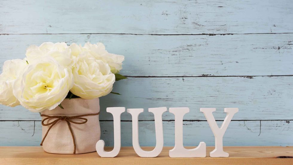 'July' letters with off-white flowers and a blue background