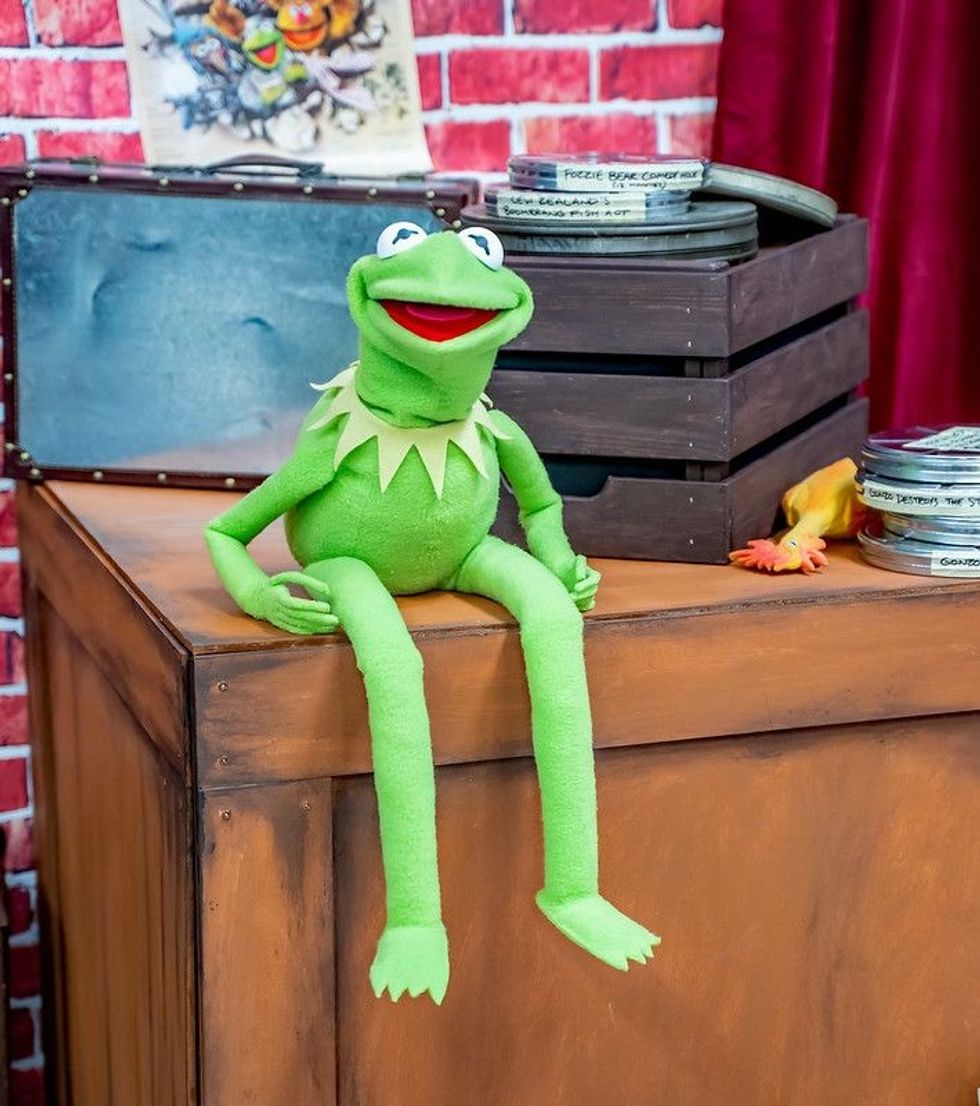 Kermit frog sitting on wooden box.