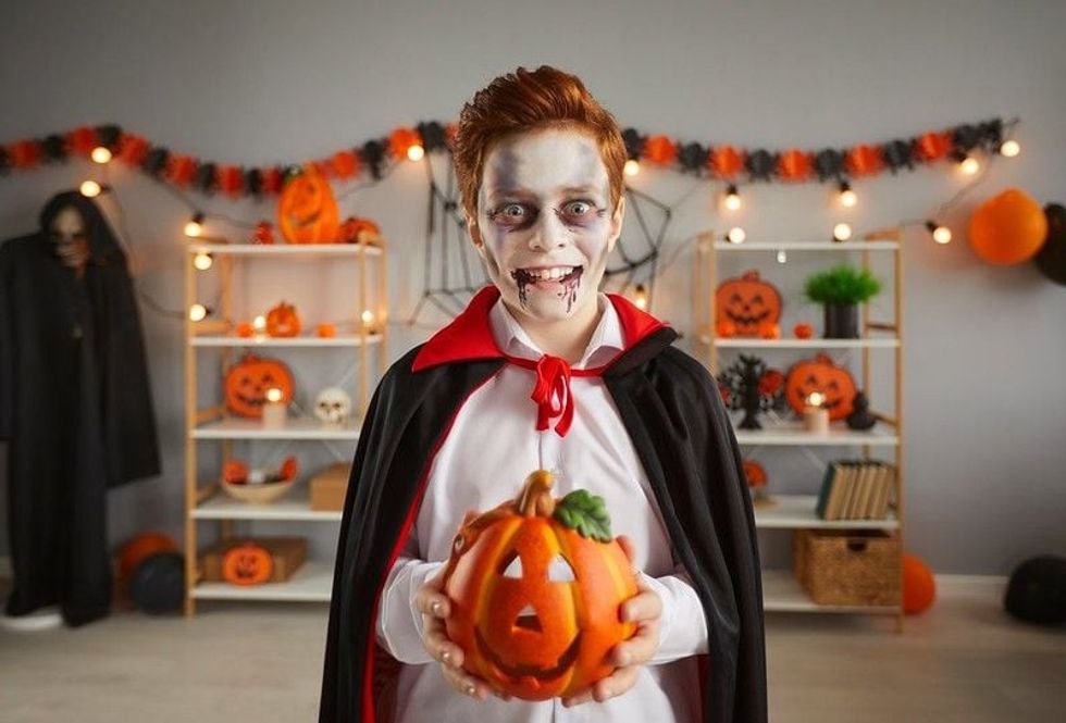 Kid in spooky Halloween vampire costume. 