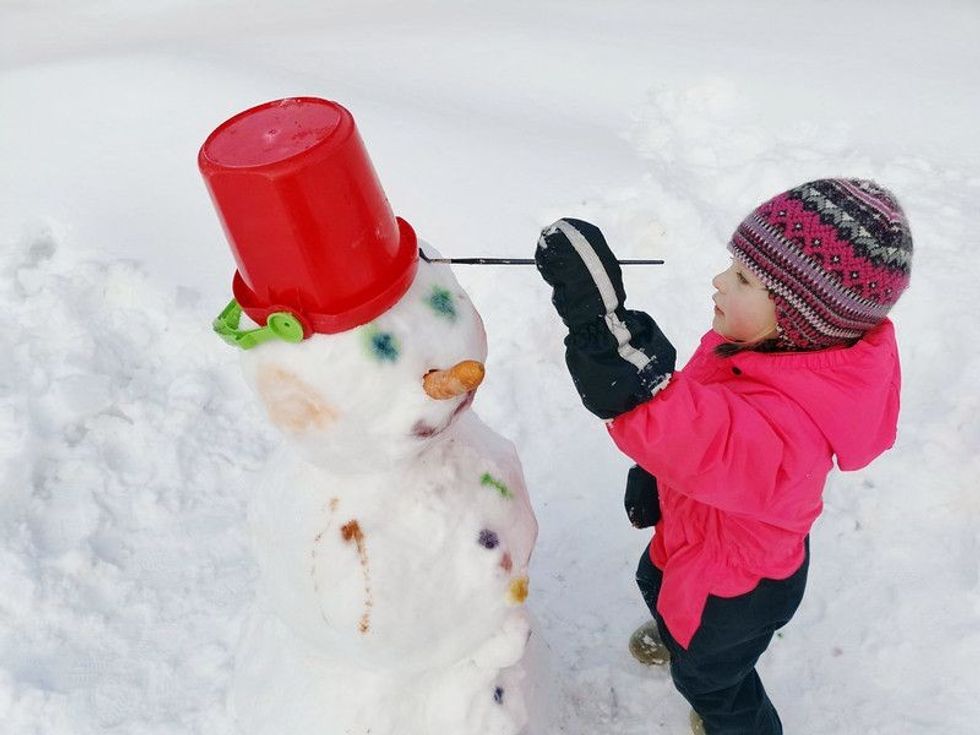 Kid making a snowman and painting it with watercolor