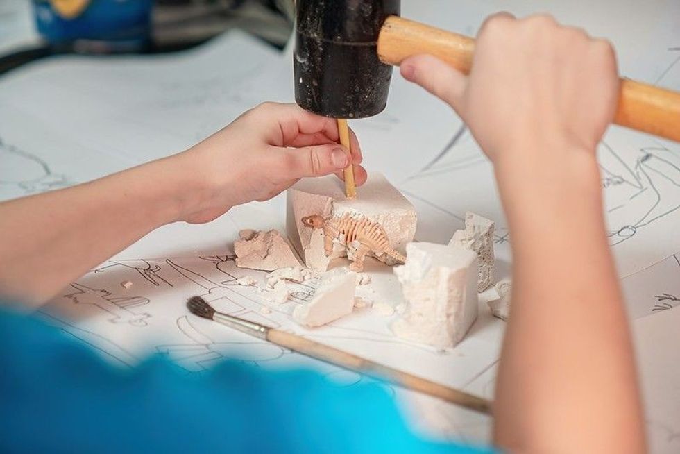 Kid playing as a paleontologist, excavating a dinosaur skeleton