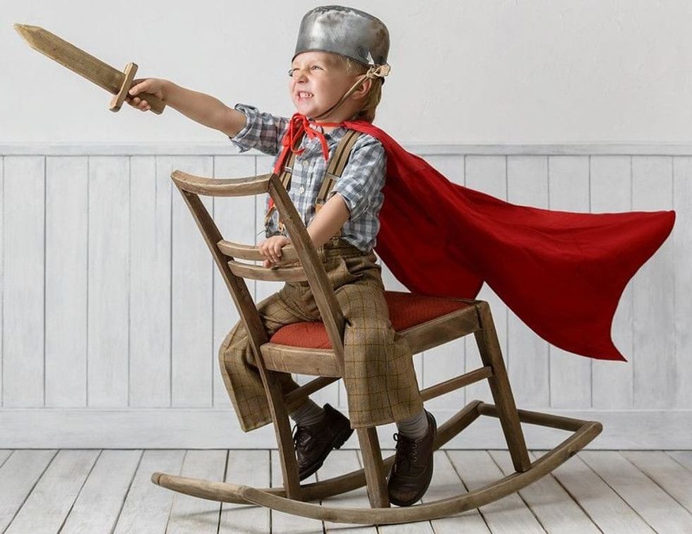 Kid wearing warrior outfit sitting on wooden chair