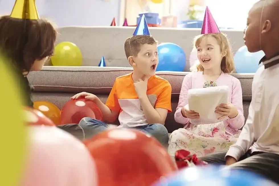 Kids at a birthday party sat on the floor playing pass the parcel.