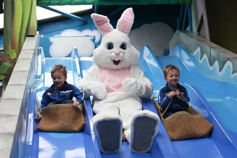 Kids riding down blue slide with BIG Sheep mascot.