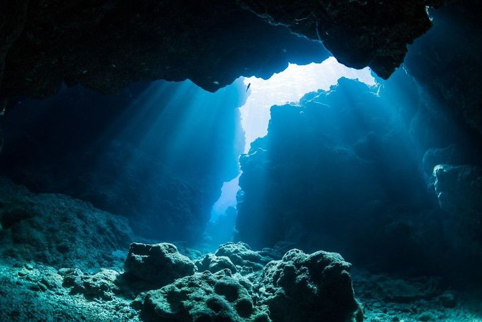 Light shining through the gaps between rocks under the ocean