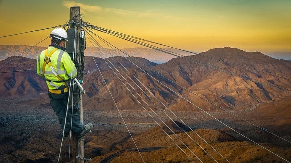 Lineman In A Remote Desert Landscape Fixing A Telephone Line