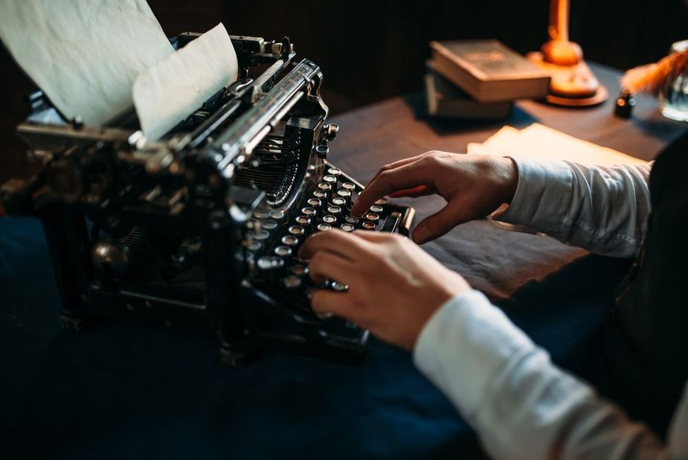 Literature author in glasses typing on typewriter