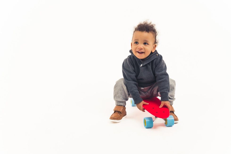 Little baby  boy sitting on a red skateboard