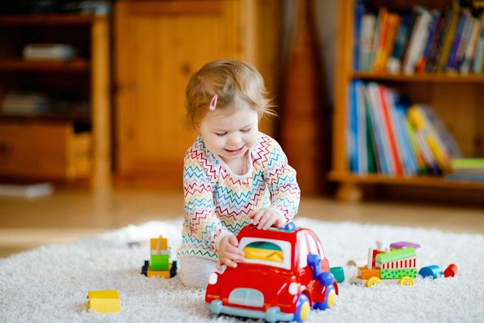 Little baby girl playing with red car toy