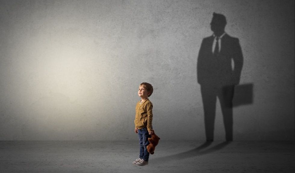 Little boy aspiring to be a businessman and illustrating his future in a big shadow