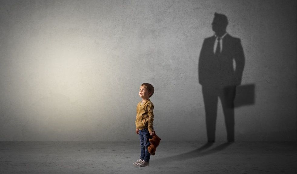 Little boy aspiring to be a businessman and illustrating his future in a big shadow