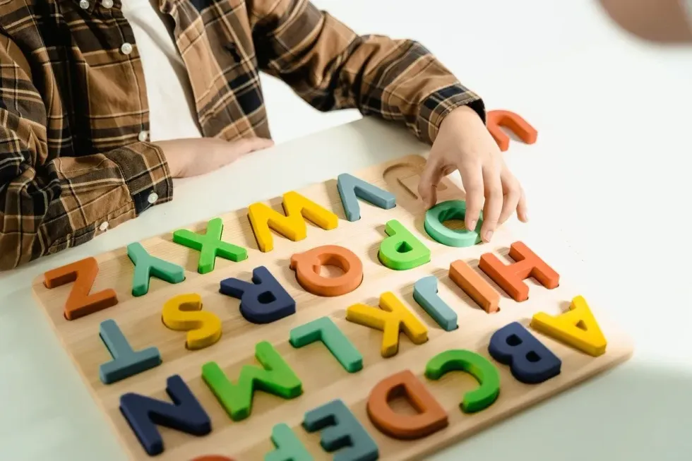 Little boy playing with colourful wooden alphabet puzzle game
