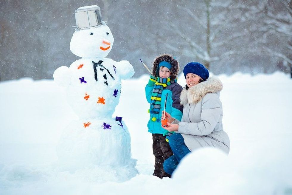 Little boy with his mother painting a snowman