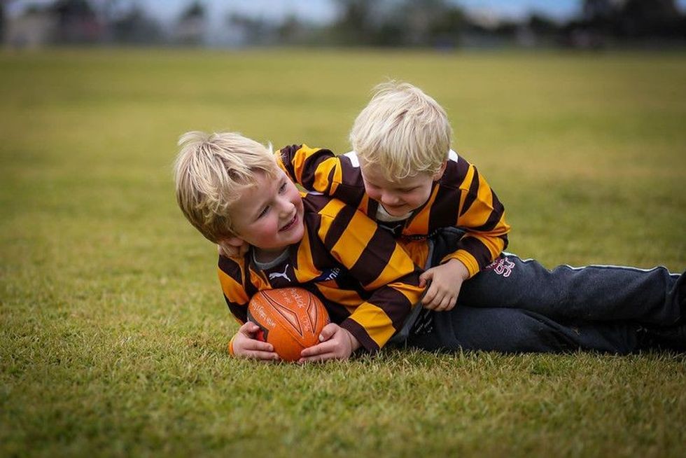 Little boys wearing uniform playing AFL football.