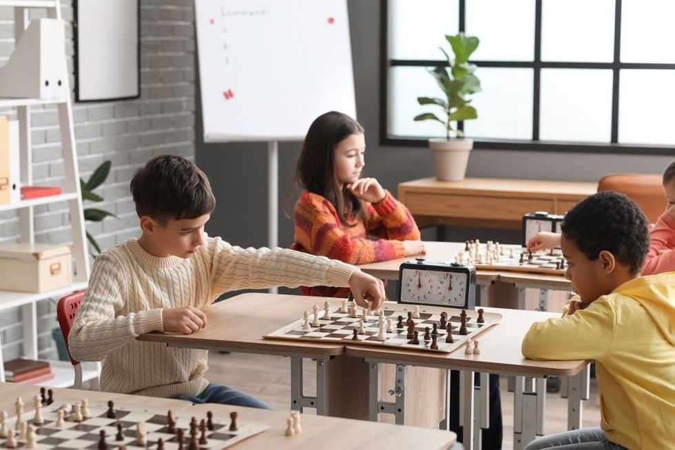 Little children playing chess during tournament in club.