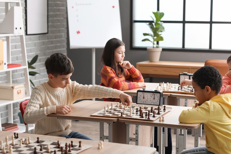 Little children playing chess during tournament in club.