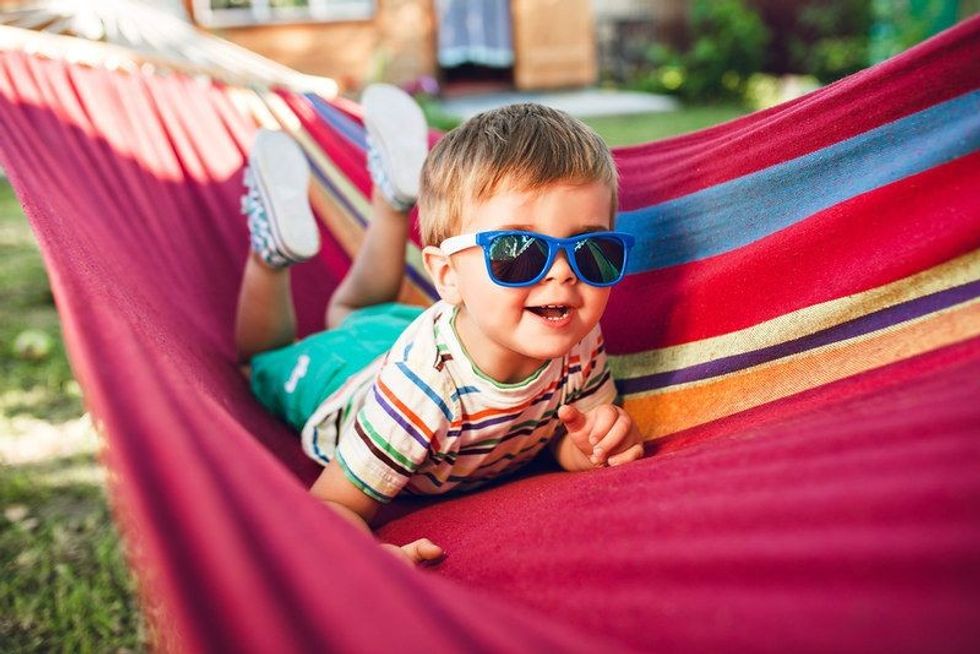 Little cute boy resting on bright hammock and having fun