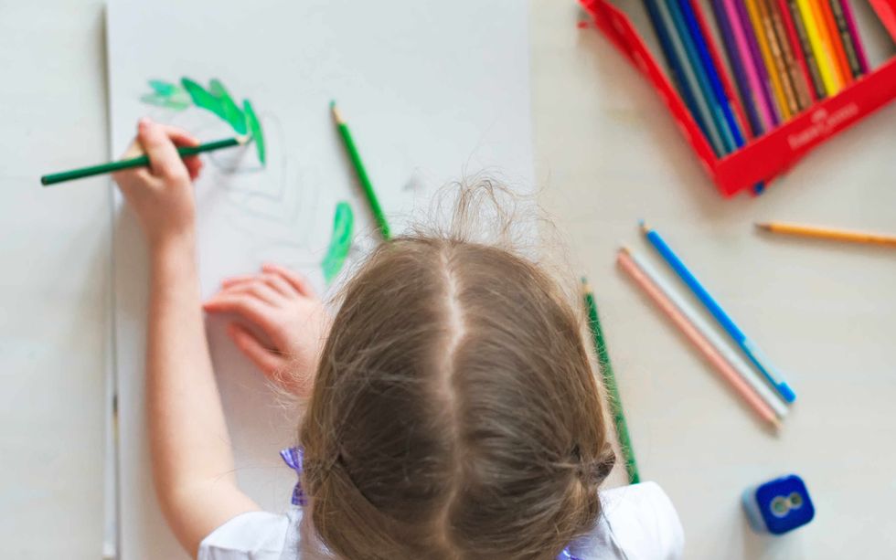 Little girl drawing with pencil at home