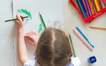 Little girl drawing with pencil at home