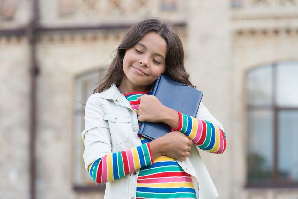 Little girl hold book.