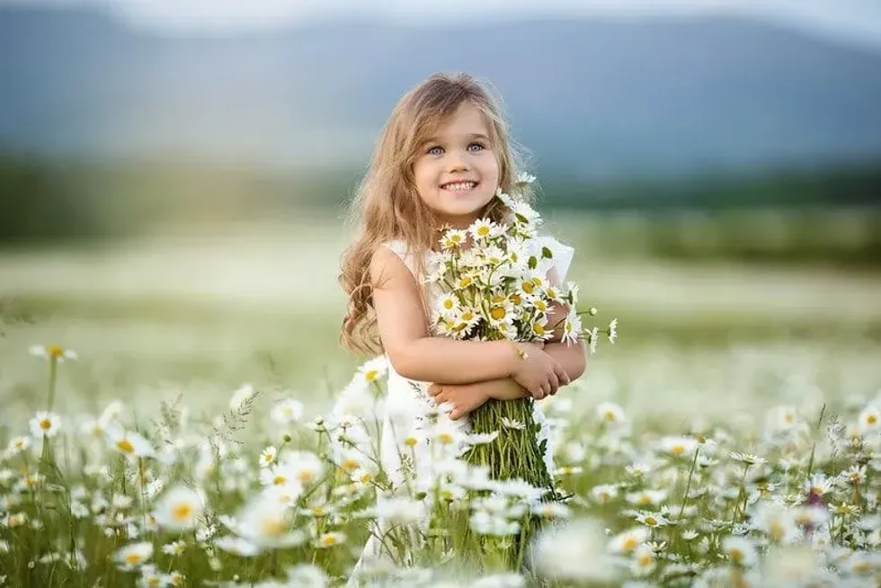 Little girl in a field of flowers holding a bouquet in her arms.