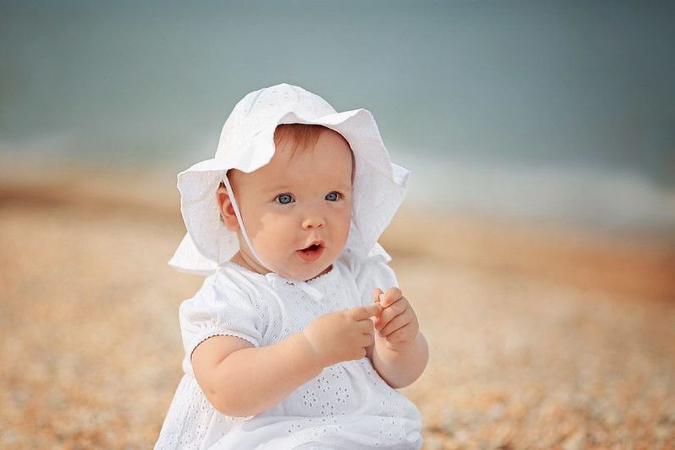 Little girl in a white hat near the sea