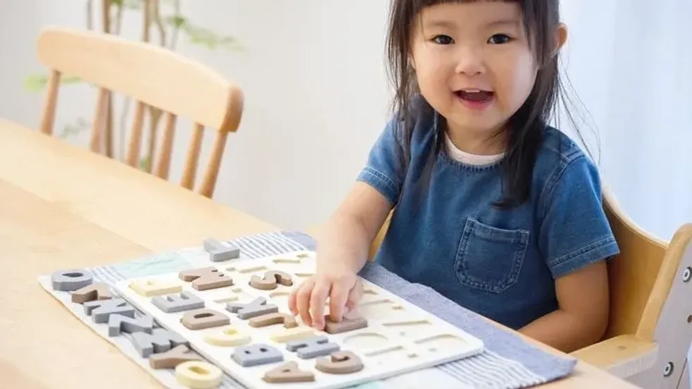 Little girl studying English with alphabet puzzles