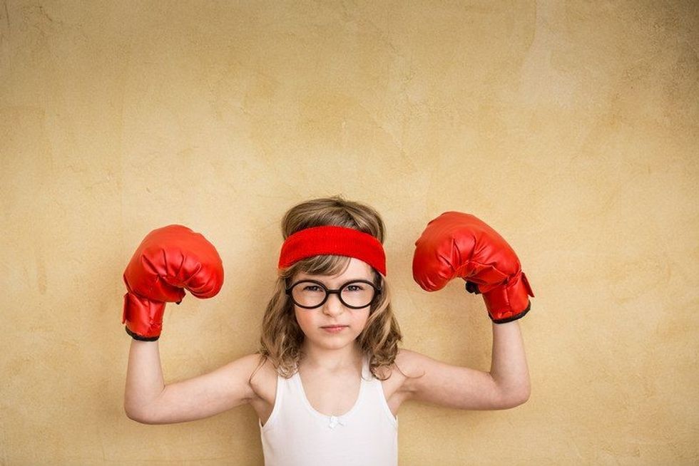 Little girl wearing red boxing gloves.